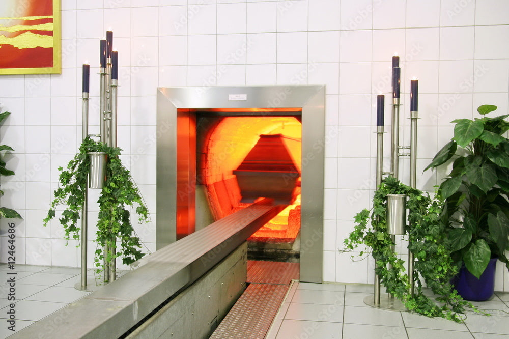 Cremation chamber with decorated plants and candles, metal casket on conveyor