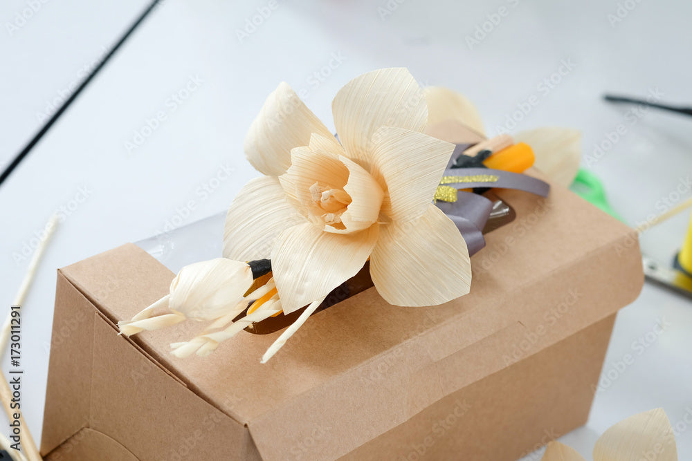 Decorative paper flower on a brown cremation urn box, memorial arrangement