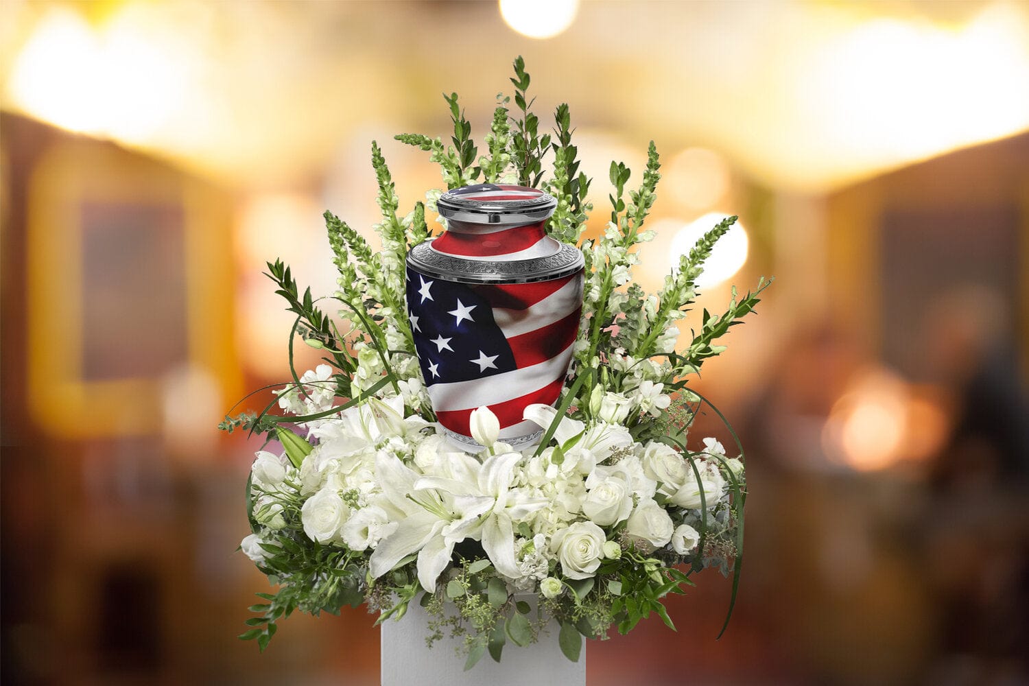 Patriotic cremation urn with American flag design, surrounded by white flowers, memorial setting