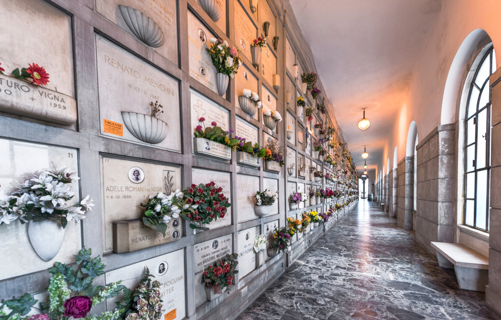 Marble columbarium wall with urn niches adorned with flowers in a peaceful corridor